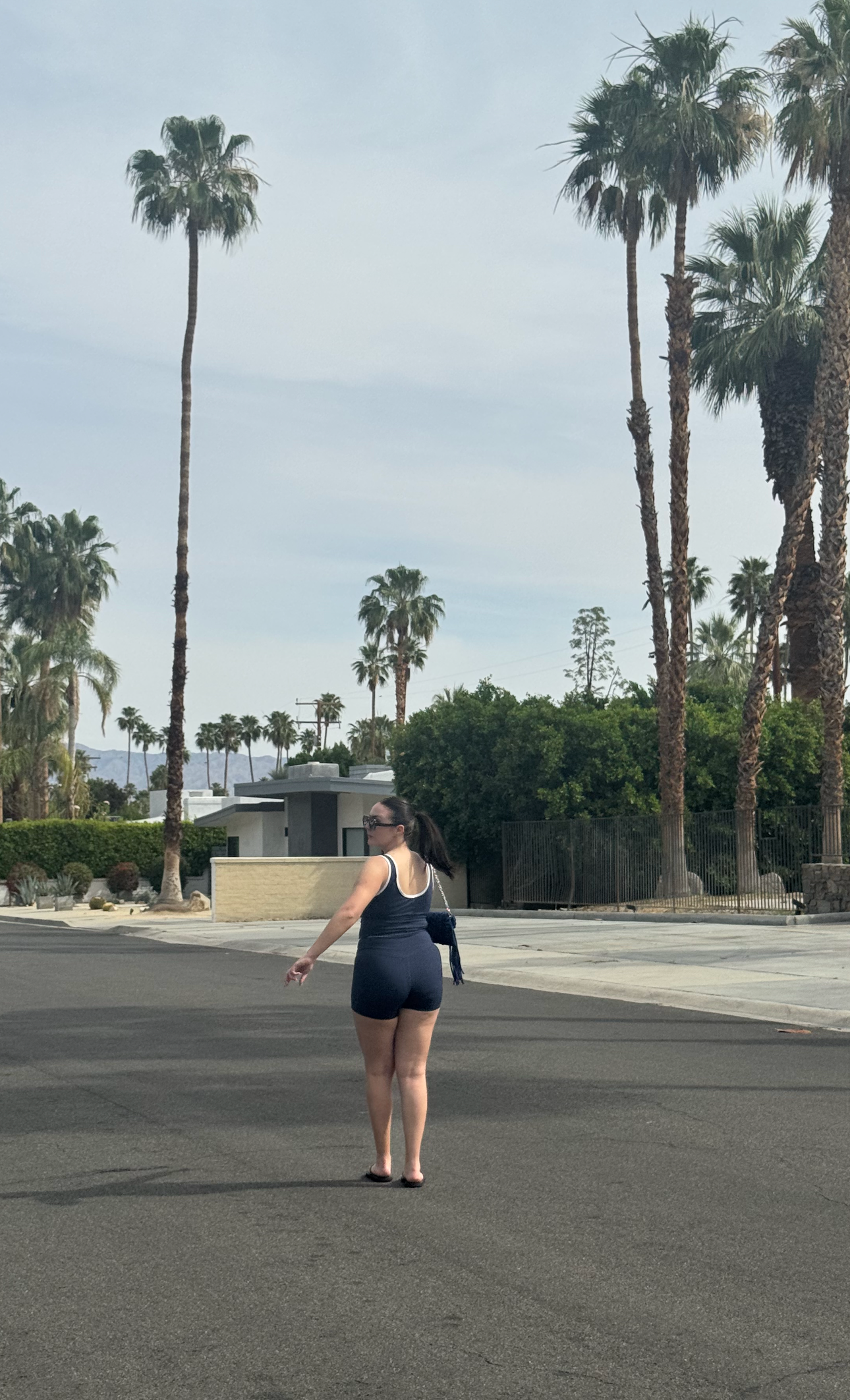 Person standing on a street with palm trees in the background