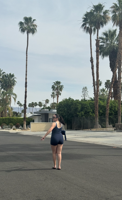Person standing on a street with palm trees in the background